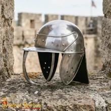 Shiny medieval knight's helmet resting on stone battlements with a blurred castle backdrop.